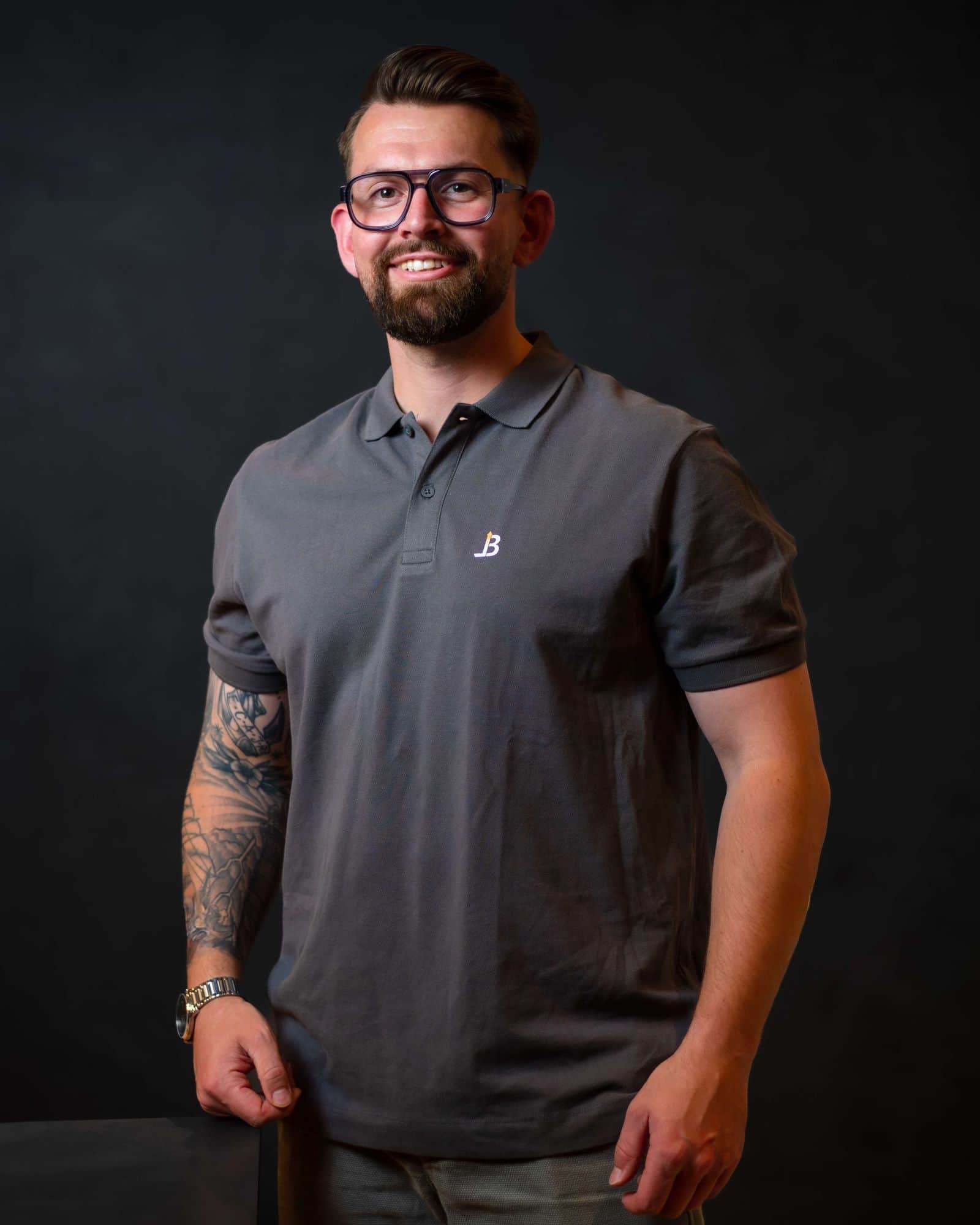 Jannik Stempnewicz im grauen Poloshirt lächelt vor dunklem Hintergrund in die Kamera